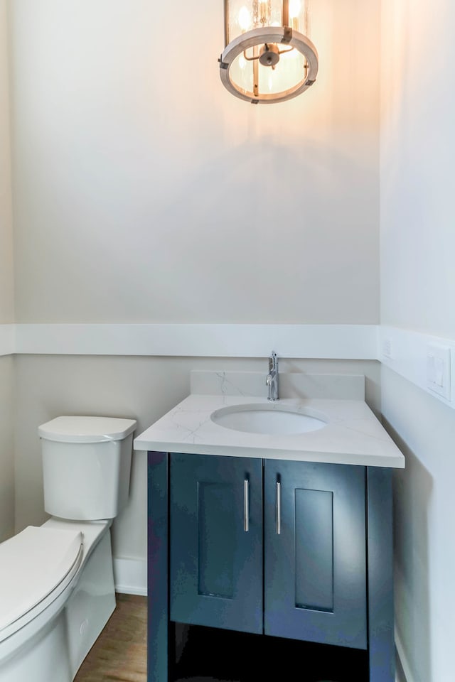 half bathroom featuring toilet, wood finished floors, and vanity