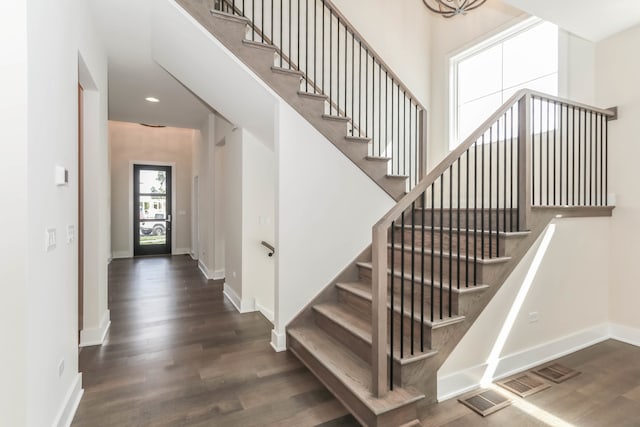 stairway featuring a high ceiling, wood finished floors, and baseboards