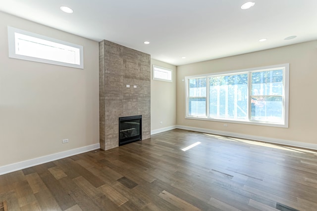 unfurnished living room featuring recessed lighting, baseboards, dark wood finished floors, and a tiled fireplace