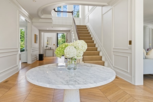 interior space featuring plenty of natural light, crown molding, and light parquet floors