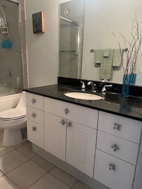 full bathroom featuring tile patterned floors, vanity, toilet, and bath / shower combo with glass door