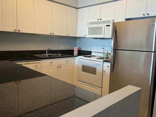 kitchen with white appliances, white cabinetry, dark stone counters, and sink