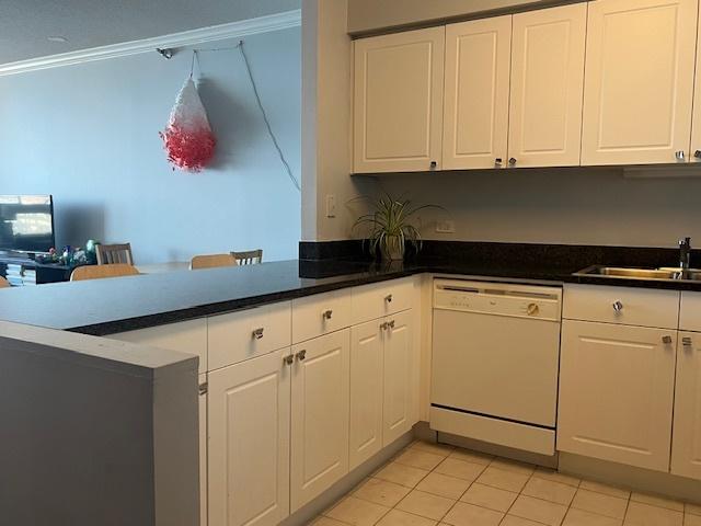 kitchen with dishwasher, white cabinets, sink, light tile patterned floors, and kitchen peninsula