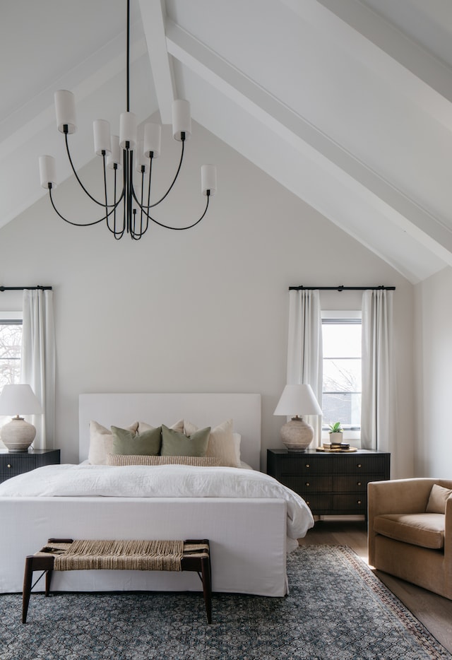 bedroom with multiple windows, vaulted ceiling with beams, and an inviting chandelier