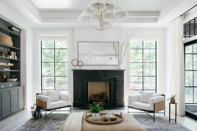 living room featuring light hardwood / wood-style floors, a raised ceiling, plenty of natural light, and a fireplace