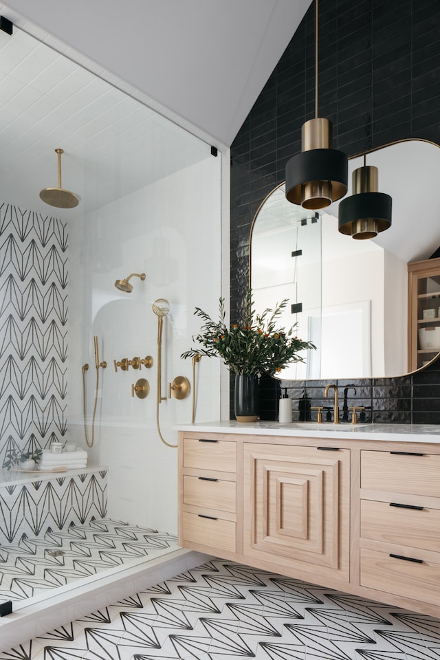 bathroom featuring vanity, tasteful backsplash, a shower, tile walls, and vaulted ceiling