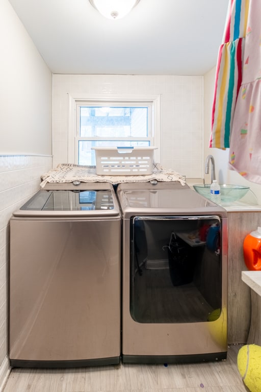 laundry area with light hardwood / wood-style floors and washing machine and clothes dryer