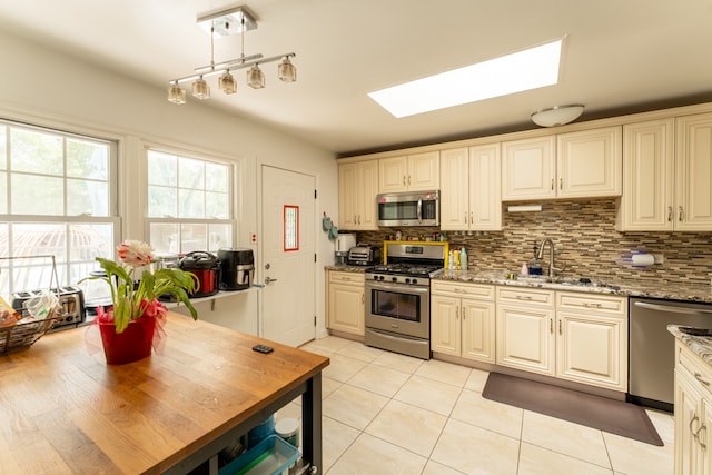 kitchen featuring tasteful backsplash, light stone counters, sink, light tile patterned flooring, and stainless steel appliances