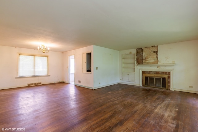 unfurnished living room featuring a notable chandelier, a brick fireplace, and wood-type flooring