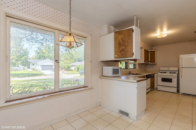 kitchen featuring sink, decorative light fixtures, white appliances, and light tile patterned floors