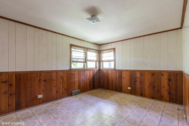 tiled spare room featuring crown molding and wooden walls