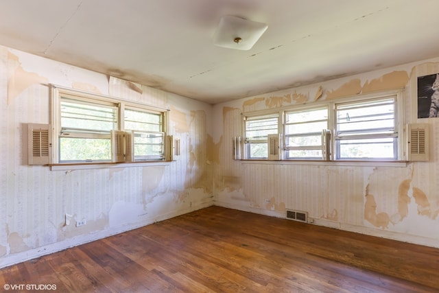 unfurnished room featuring plenty of natural light and dark hardwood / wood-style flooring