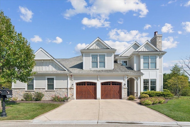 view of front of home featuring driveway, stone siding, a front lawn, and board and batten siding