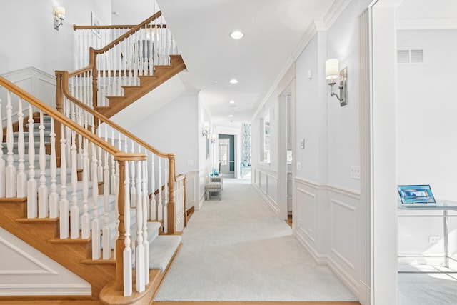 interior space with light carpet, ornamental molding, and a decorative wall