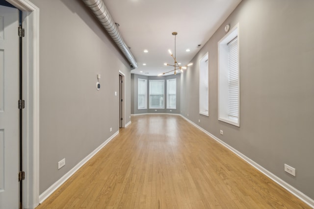 unfurnished room with light hardwood / wood-style floors and an inviting chandelier