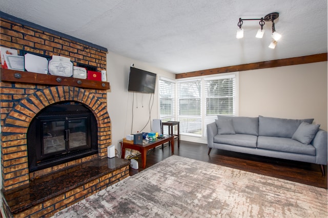 living room featuring a textured ceiling, a brick fireplace, dark wood-type flooring, and brick wall