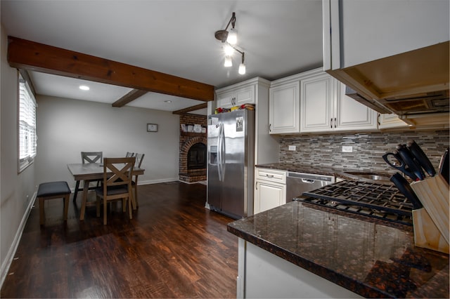 kitchen featuring backsplash, stainless steel appliances, white cabinets, dark wood-type flooring, and a brick fireplace