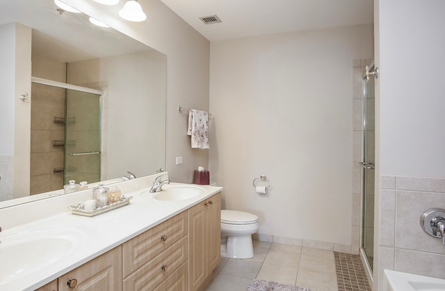 bathroom with vanity, toilet, tile patterned floors, and a shower with door