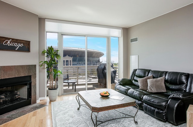 living room featuring a tiled fireplace and light hardwood / wood-style floors