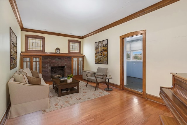 living room with light wood-type flooring, a fireplace, baseboards, and crown molding