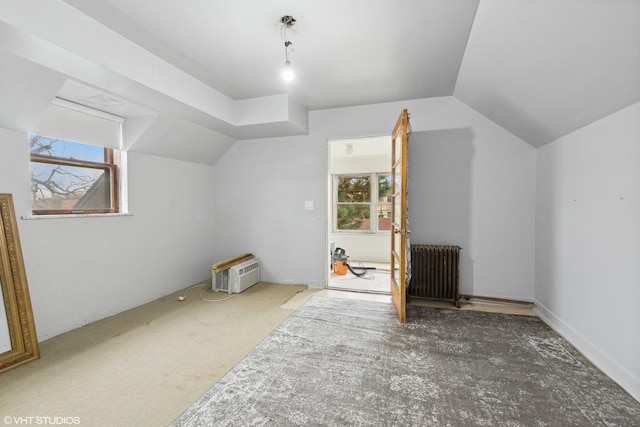 bonus room featuring carpet floors, lofted ceiling, radiator, and an AC wall unit