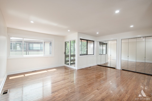 unfurnished bedroom featuring light hardwood / wood-style floors, access to outside, and multiple closets