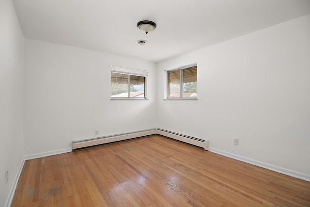 unfurnished room with light hardwood / wood-style floors and a baseboard heating unit