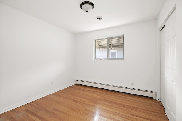 unfurnished bedroom with light hardwood / wood-style flooring, a closet, and baseboard heating