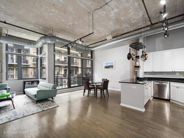 kitchen featuring white cabinetry, dark wood-type flooring, a towering ceiling, and stainless steel dishwasher