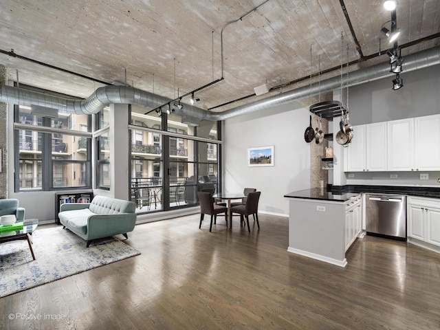 kitchen with dark countertops, baseboards, dark wood finished floors, white cabinetry, and stainless steel dishwasher