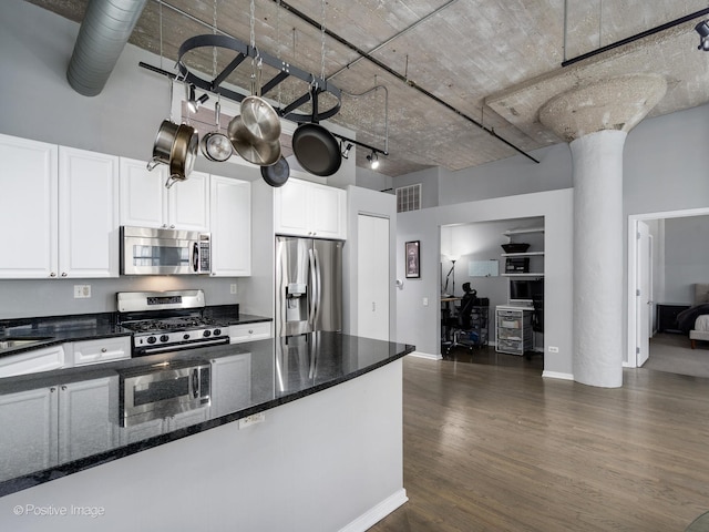 kitchen featuring a high ceiling, appliances with stainless steel finishes, dark wood-style flooring, and white cabinetry