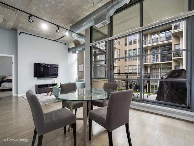 dining room featuring hardwood / wood-style flooring, a wall of windows, and a healthy amount of sunlight