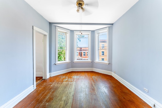 empty room with ceiling fan and dark hardwood / wood-style flooring