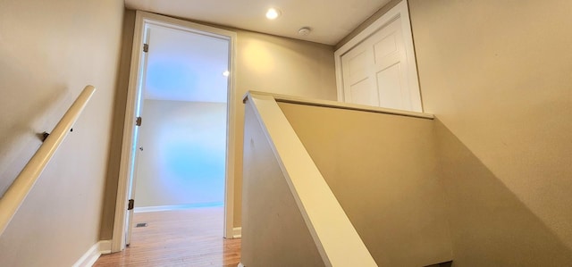 staircase featuring baseboards, wood finished floors, and recessed lighting