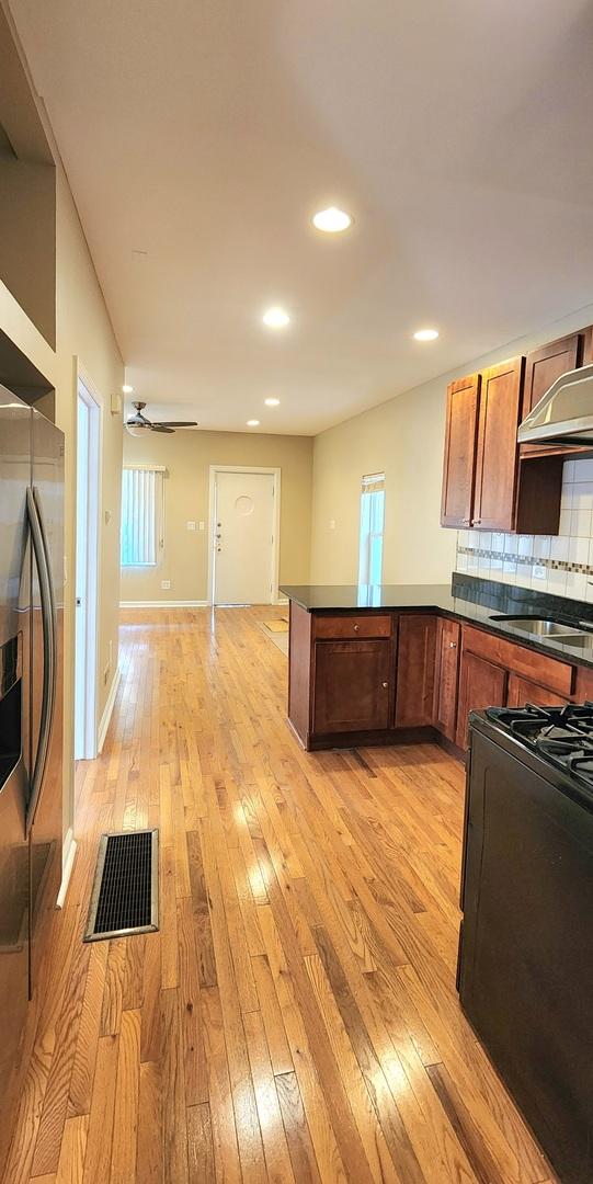 kitchen with a sink, light wood-type flooring, dark countertops, and range with gas cooktop