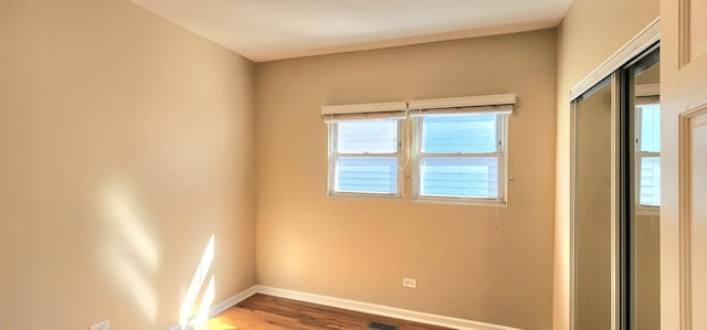 spare room with baseboards, wood finished floors, and a healthy amount of sunlight