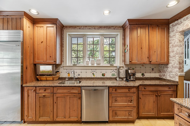 kitchen with sink, stainless steel appliances, light stone countertops, and decorative backsplash