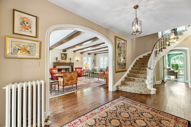 entryway featuring dark hardwood / wood-style flooring, an inviting chandelier, radiator heating unit, and beam ceiling