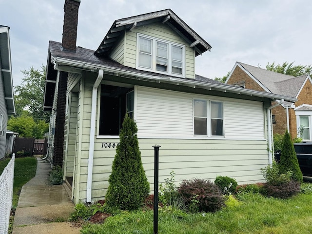 view of side of home featuring a chimney and fence