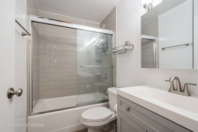 full bathroom with bath / shower combo with glass door, vanity, and toilet