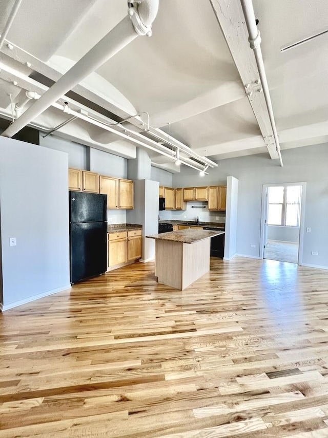 kitchen featuring a kitchen island, light wood-style floors, open floor plan, freestanding refrigerator, and light brown cabinetry