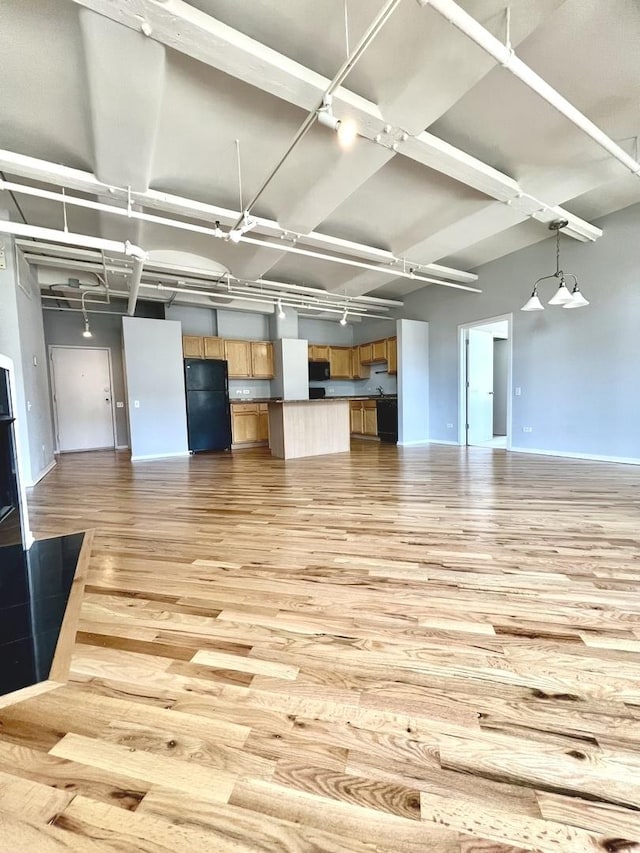 interior space featuring a high ceiling, light wood-style flooring, and baseboards