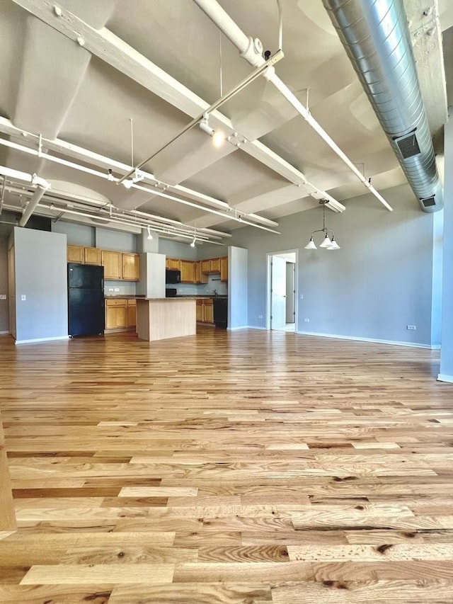 interior space with light wood finished floors, a high ceiling, rail lighting, and baseboards