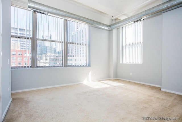 spare room with baseboards, visible vents, a city view, and carpet flooring