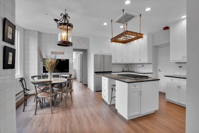 kitchen with a kitchen island, stainless steel appliances, white cabinets, and light hardwood / wood-style floors