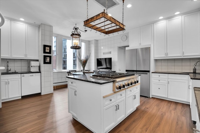 kitchen with light wood-type flooring, tasteful backsplash, white cabinetry, stainless steel appliances, and a center island