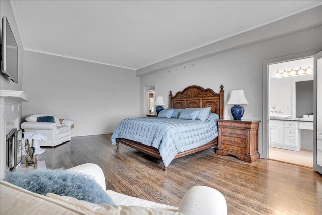 bedroom featuring wood-type flooring, ensuite bathroom, and crown molding