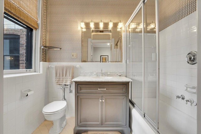 full bathroom with vanity, tile walls, toilet, tile patterned floors, and enclosed tub / shower combo