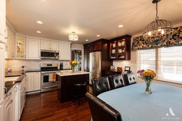 kitchen featuring sink, dark wood-type flooring, stainless steel appliances, a center island, and decorative light fixtures