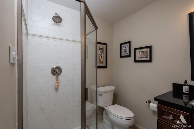 bathroom featuring a shower with door, vanity, and toilet